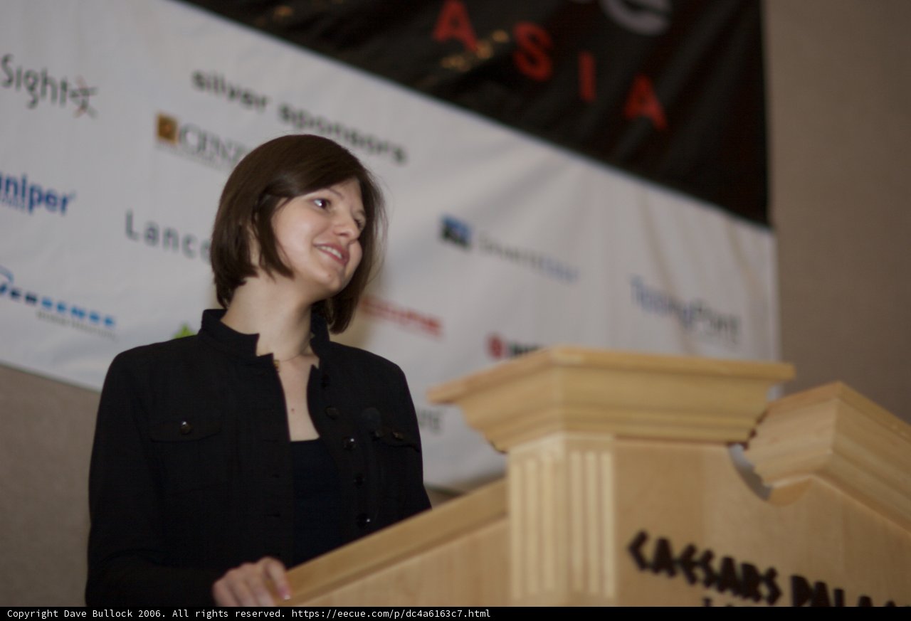 Leading the Crowd Caption: A female speaker addresses the audience from the podium with her microphone at the Black Hat 2 conference in 2006.
