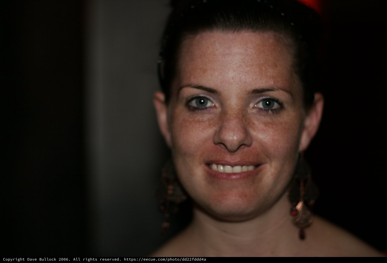 Freckled Beauty Smiling in Dark Indoor Setting