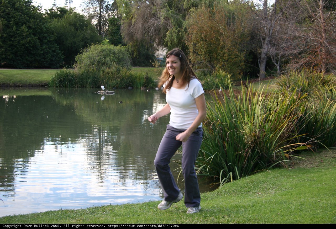 Woman Dancing Joyfully by a Tranquil Park Pond