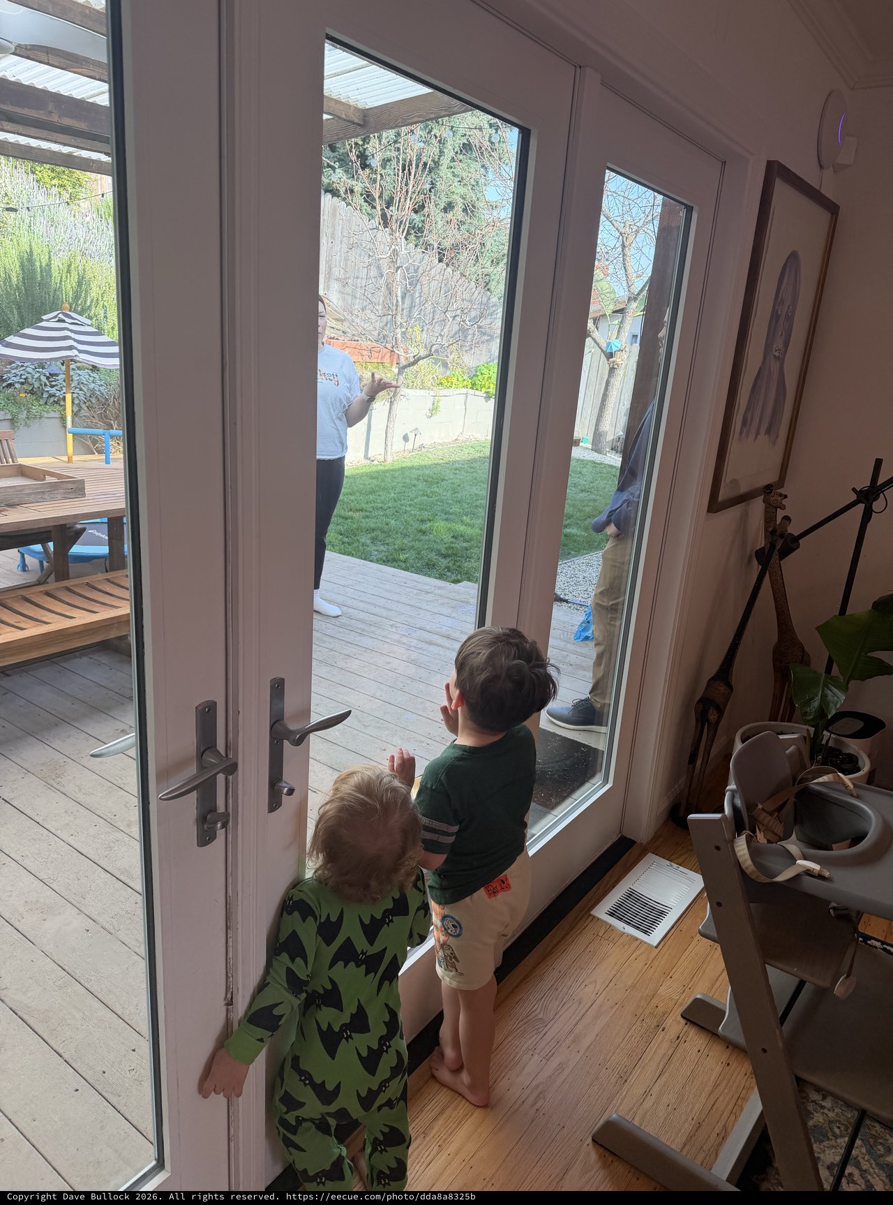 Two Children Watching Parents Work in Backyard