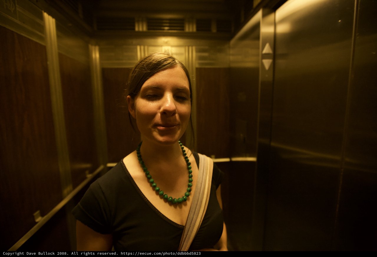 Serene Woman in Golden-Lit Vintage Elevator