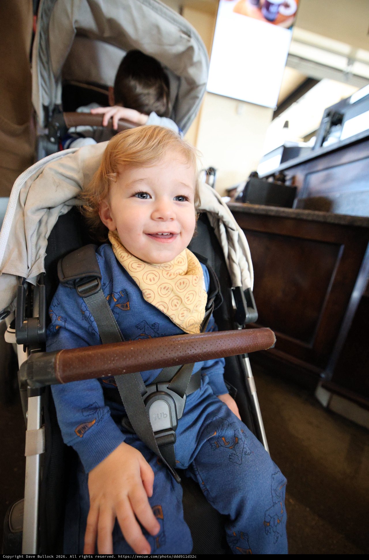 Smiling Toddler in Double Stroller at Restaurant