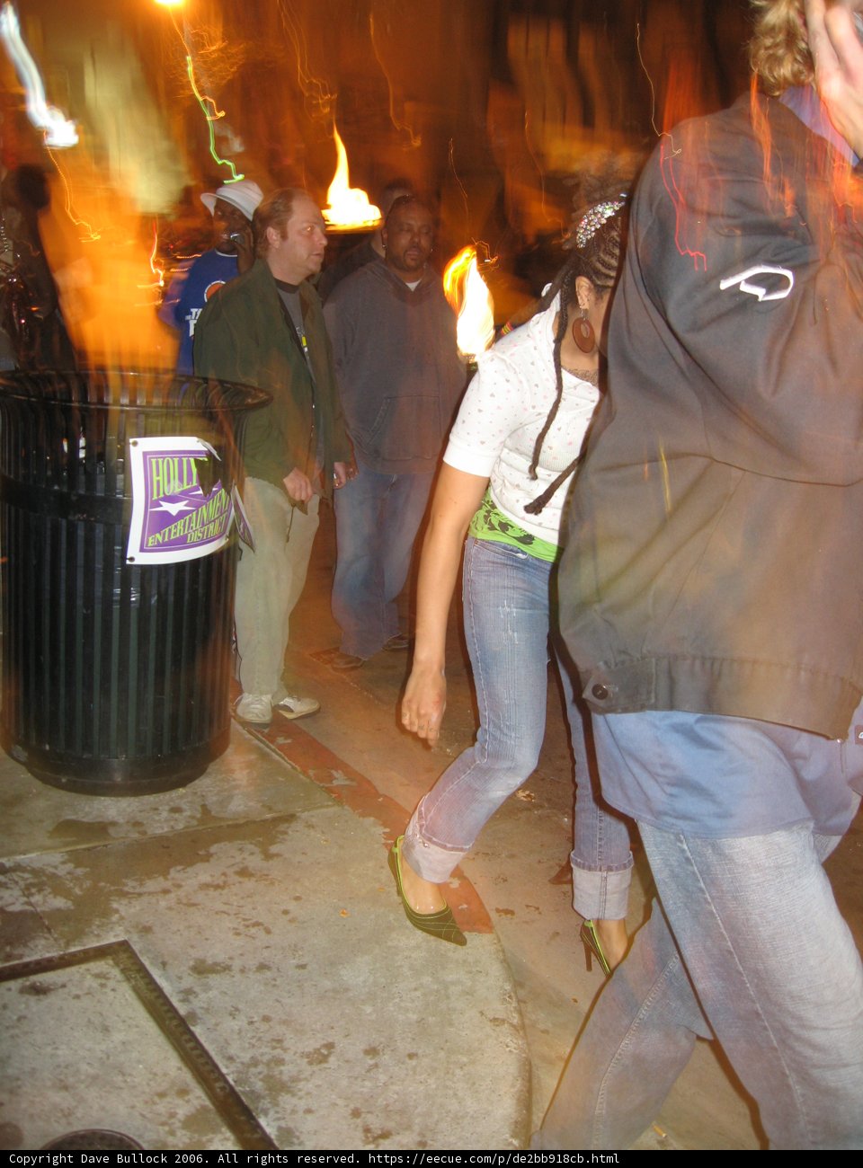 Man Walking Down Street with Fire in Hand
