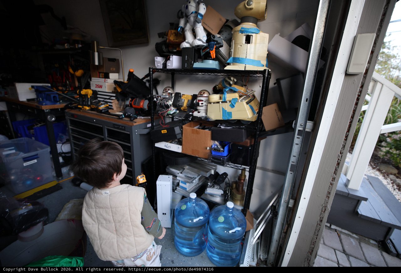 Young Child Exploring Cluttered Workshop Shelving Unit