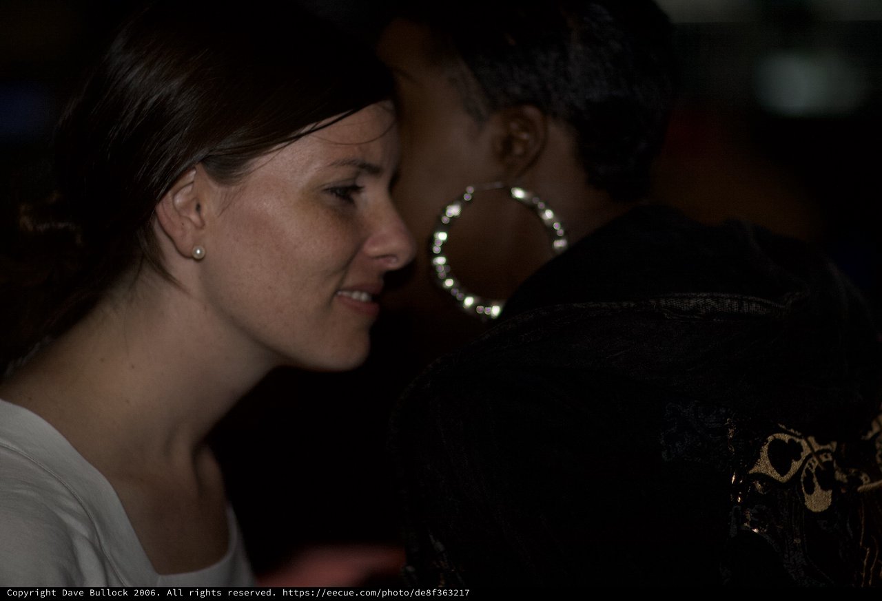 Two Women in Conversation at Dimly Lit Venue