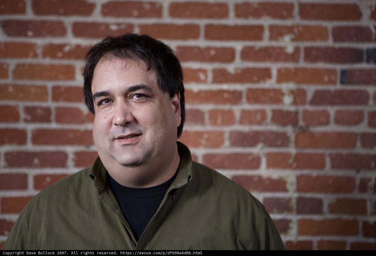 Green Shirted Man Posing in Front of Brick Wall