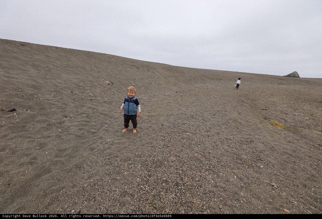 Toddler Smiling on Vast Gray Sand Dune