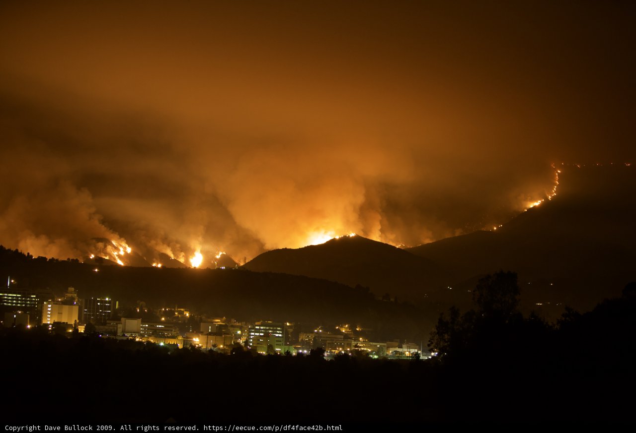 Scorching flames devour the night sky from atop a hill