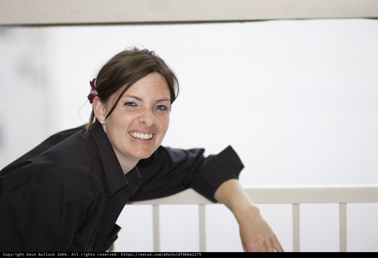 Smiling Woman Leaning on White Railing Outdoors