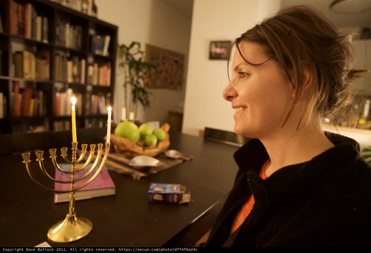 Woman Smiling by Hanukkah Menorah Candlelight