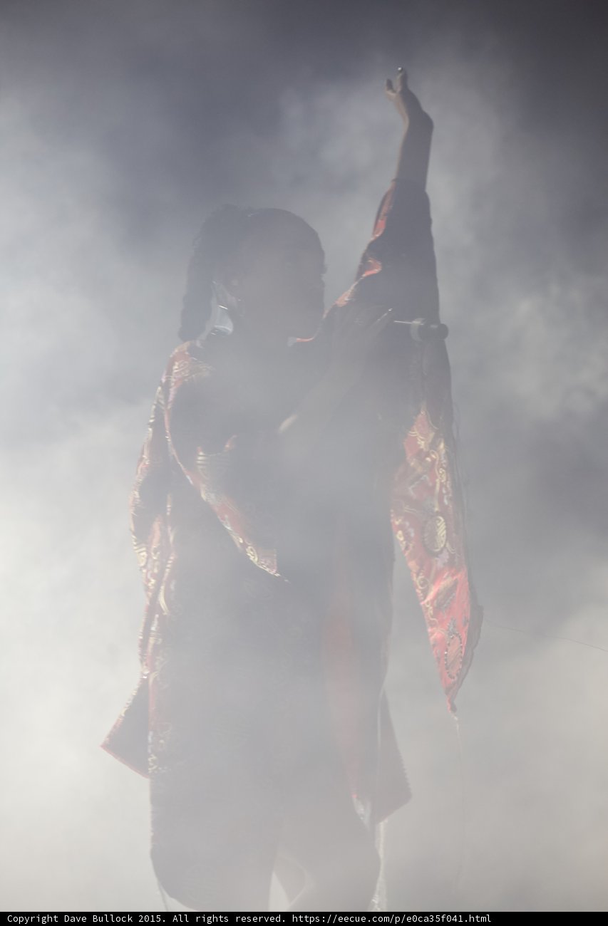 FKA twigs Powerful Silhouette Arm Raised High Singing Red Brocade Kimono Braided Ponytails Heavy White Backlit Haze
