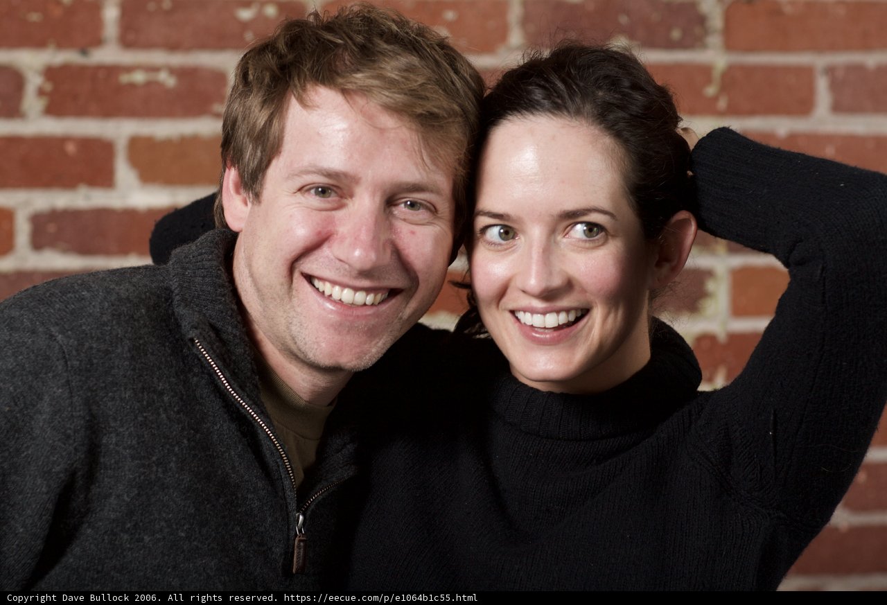 Smiling Couple Poses in Front of Brick Wall