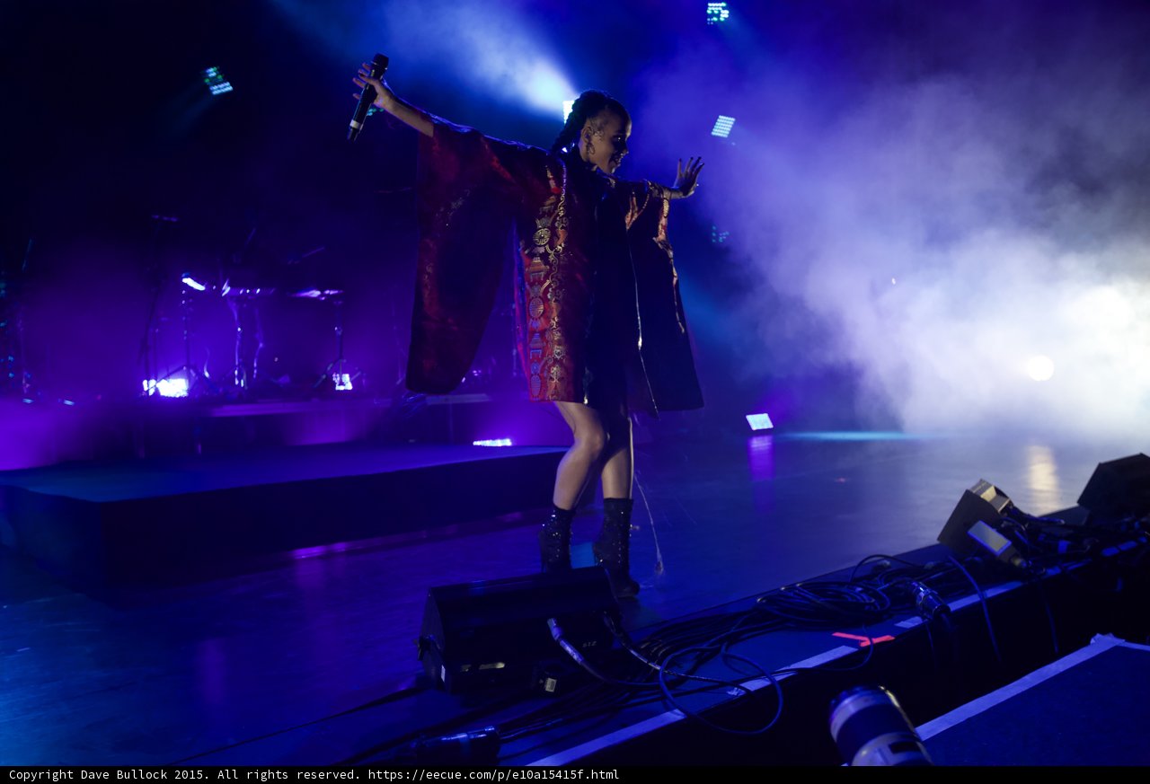 FKA twigs Dynamic Full Body Arms Spread One Arm Raised Microphone Expressive Hand Red Brocade Kimono Black Bodysuit Boots Blue Purple Lighting Haze