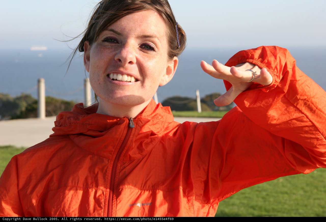 Smiling Woman in Orange Jacket by the Coast