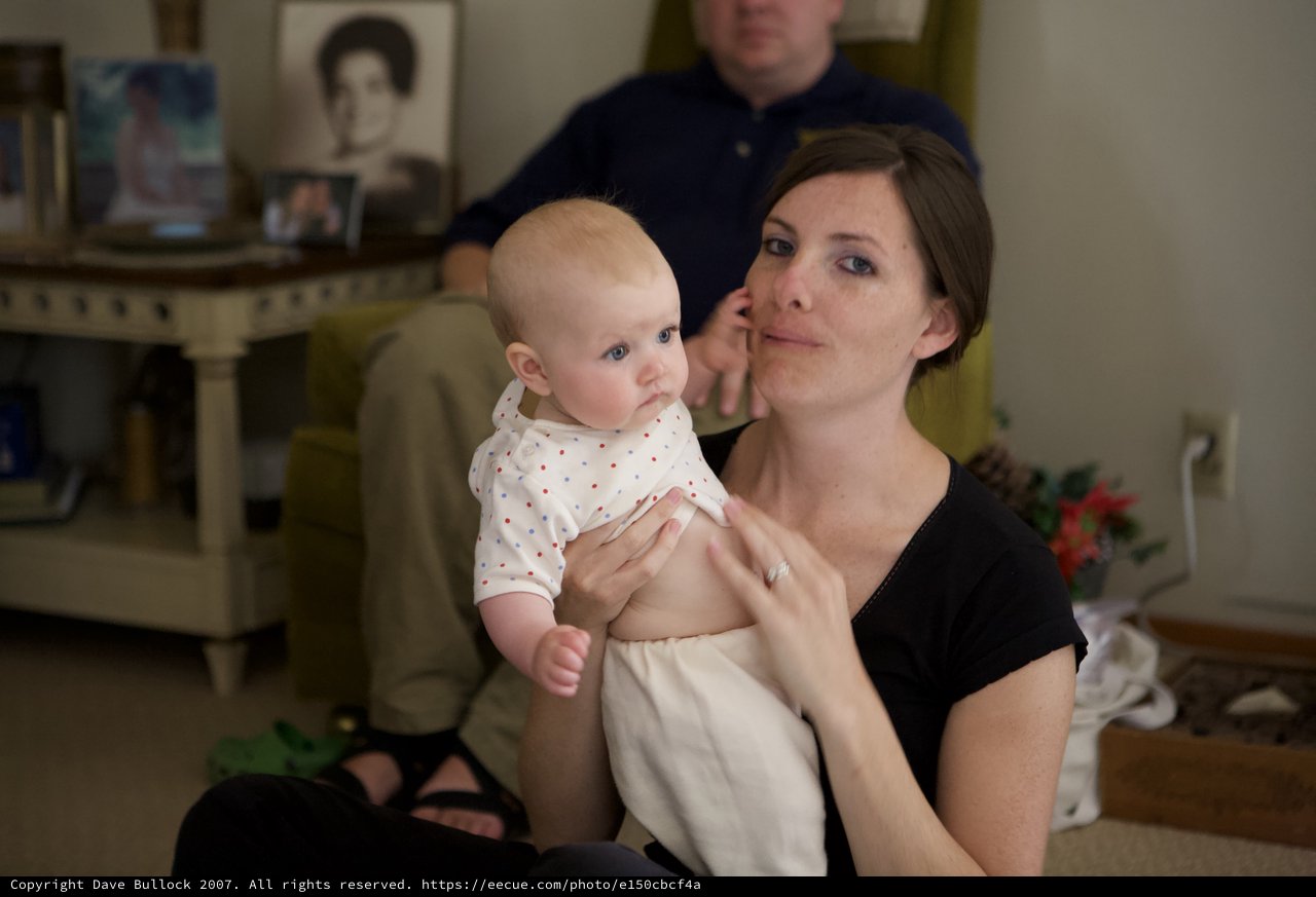 Mother Holding Infant at Family Gathering Indoors