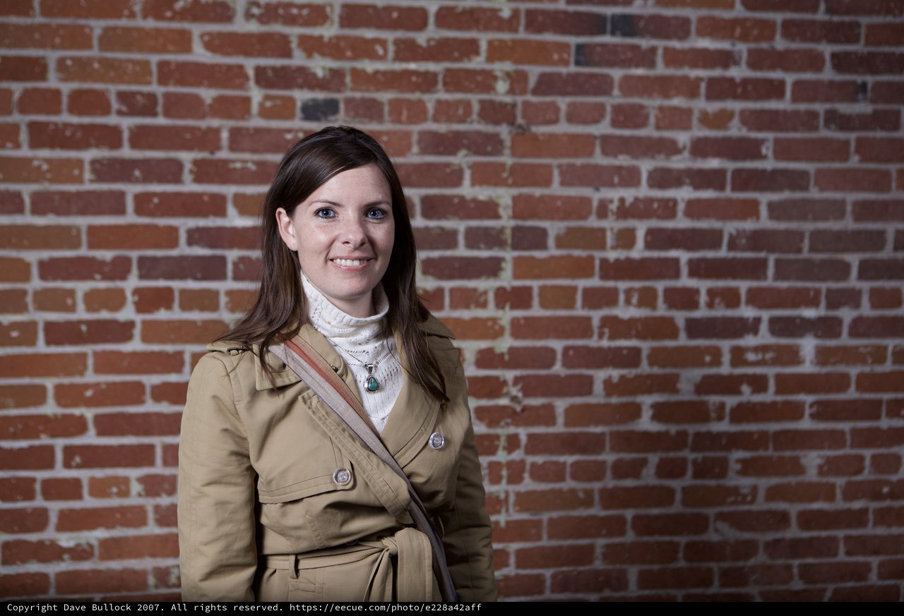 Young Woman Smiling Against Rustic Brick Wall
