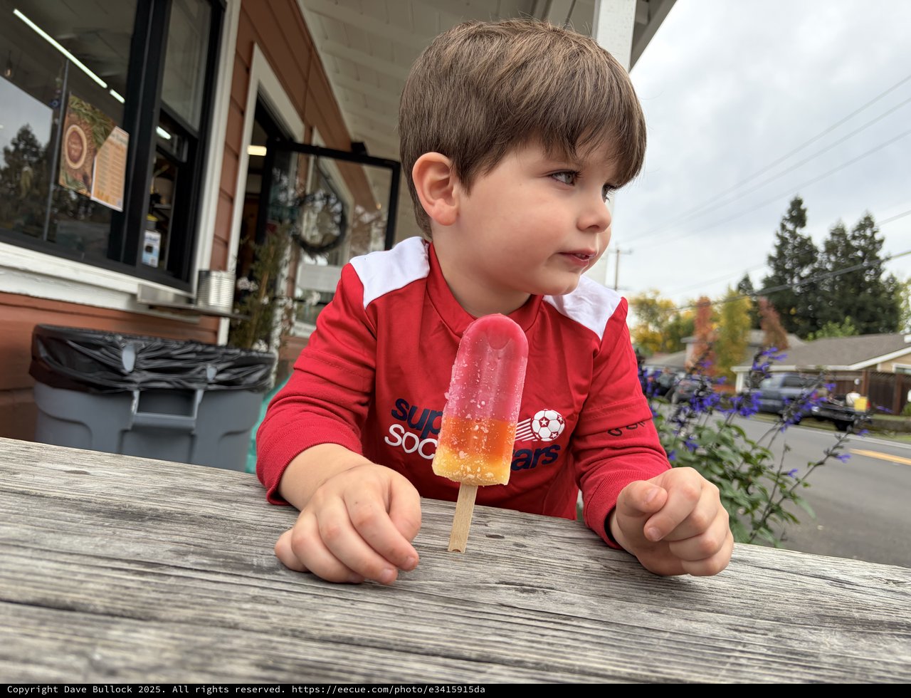 Young Boy Enjoying Colorful Popsicle on Outdoor Deck
