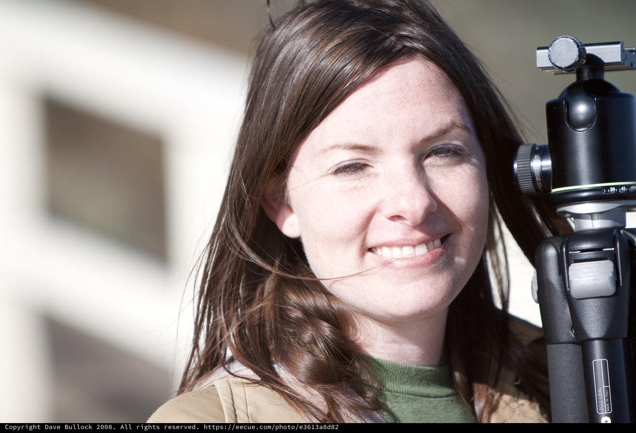 Smiling Photographer with Tripod in Sunlight