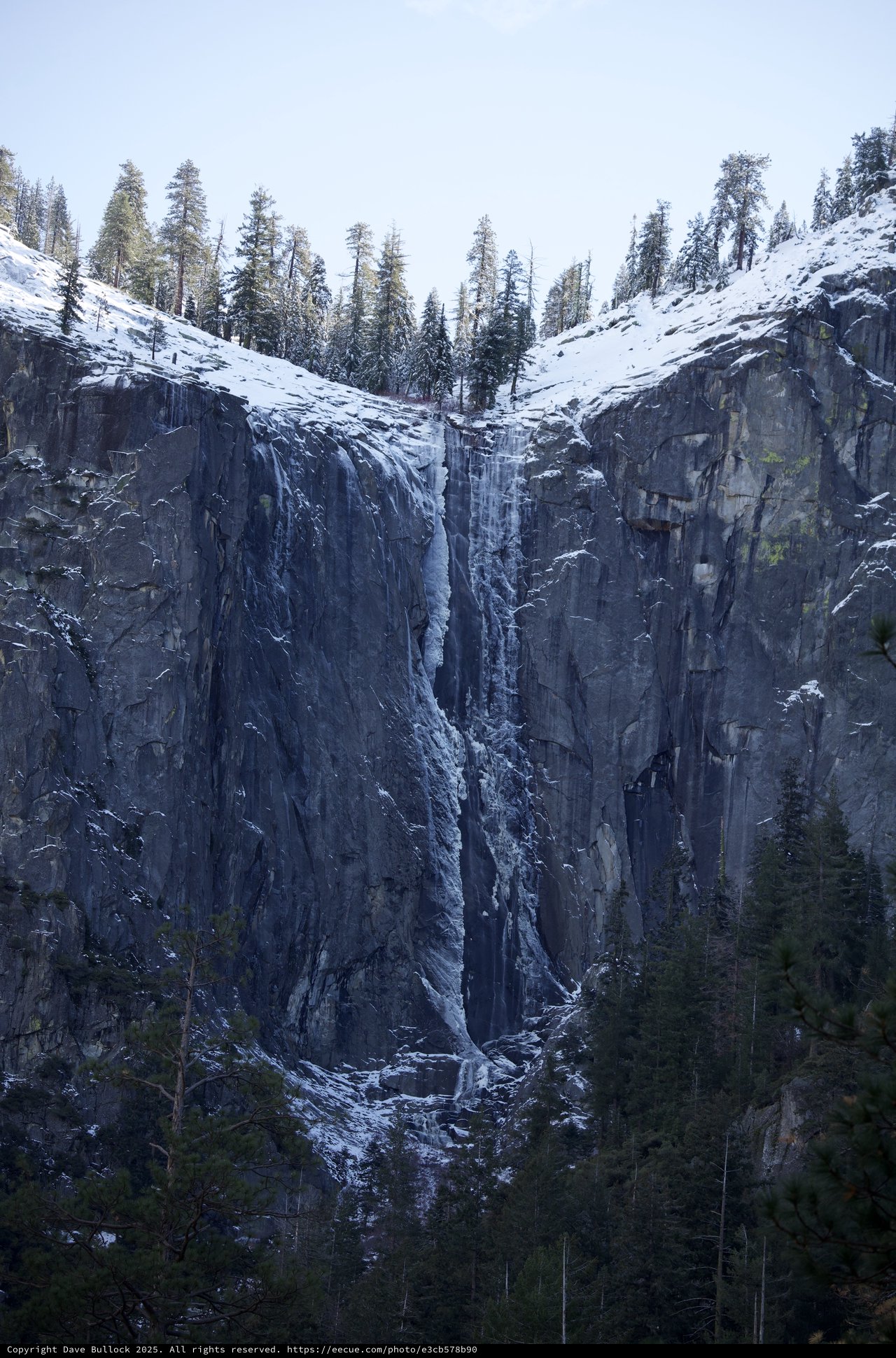 Frozen Waterfall Cascading Down Snow-Covered Basalt Cliffs
