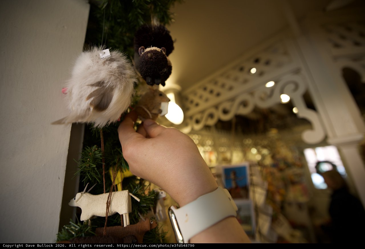 Hand Placing Festive Angel Ornament on Christmas Tree