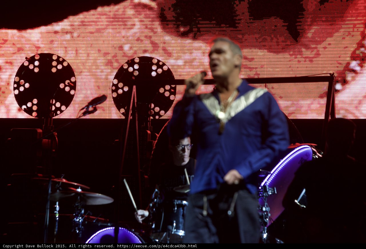 Morrissey Motion Blur Blue Shirt Drummer Glasses Behind LED Head Purple Two Circular Lights Red Screen
