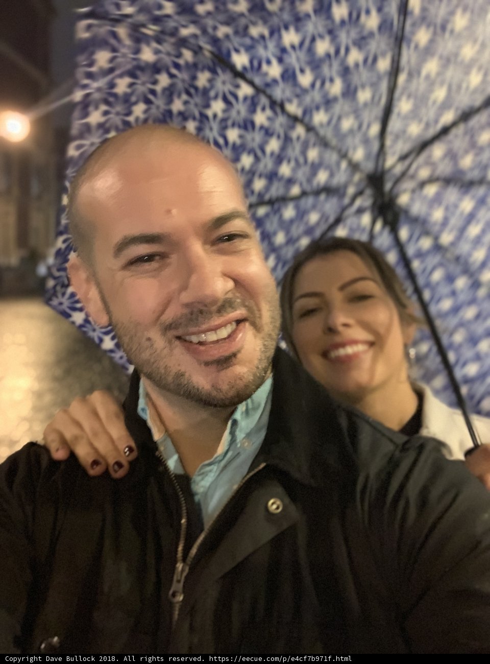 Smiling Couple Captures Moment with Umbrella Selfie