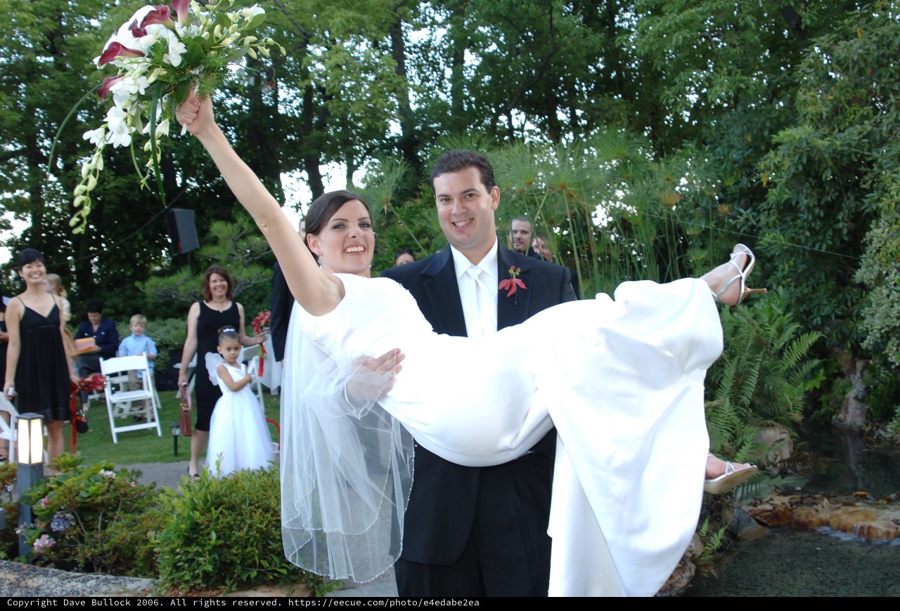Groom Carries Jubilant Bride After Outdoor Garden Wedding