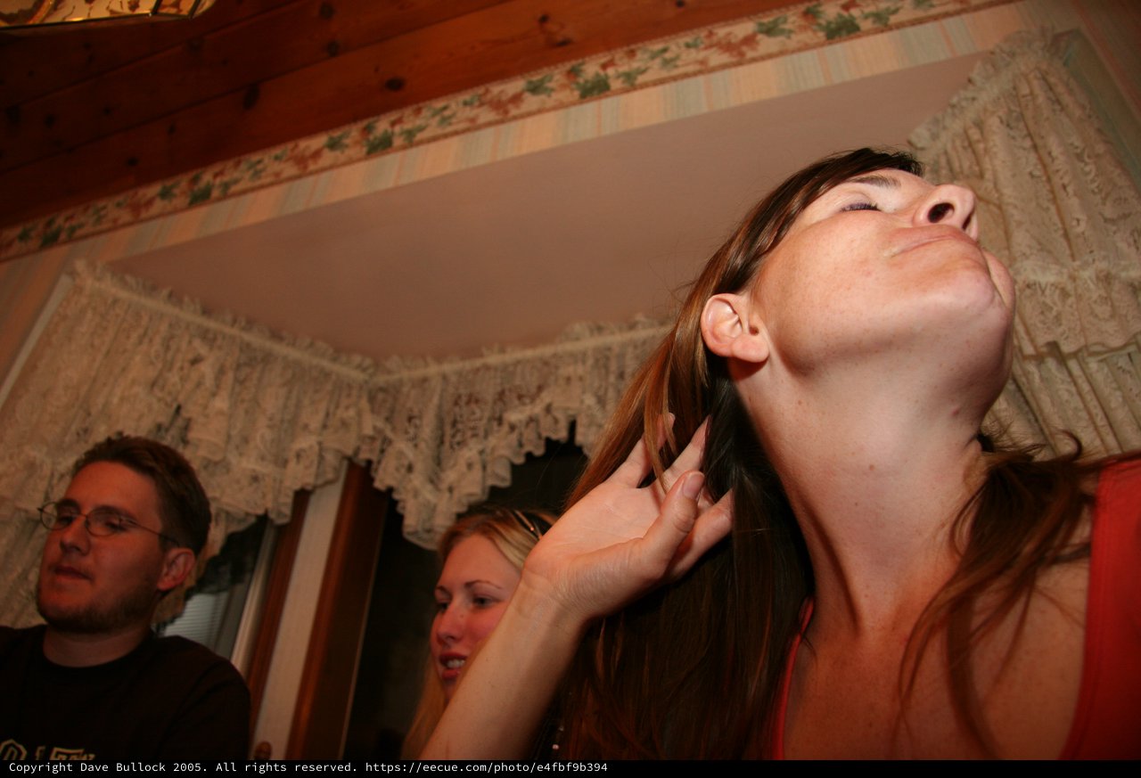 Woman Tilts Head Back at Indoor Gathering