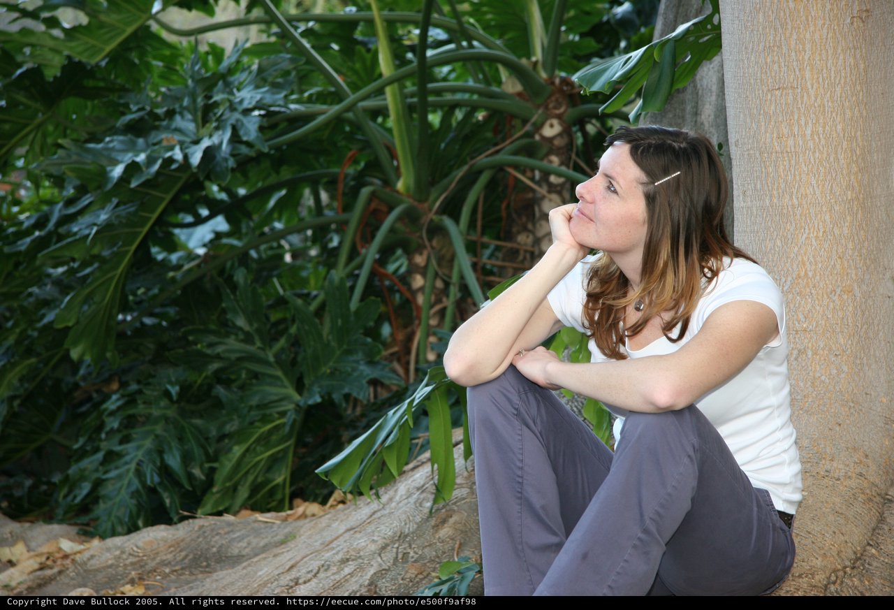 Contemplative Woman Resting Against Wall in Tropical Garden