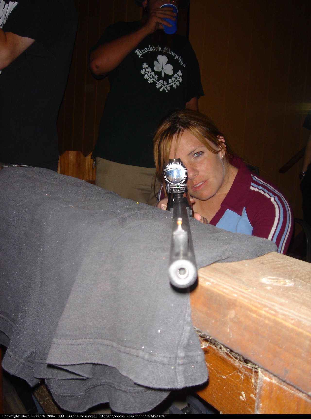 Woman Aiming Rifle Through Scope Indoors