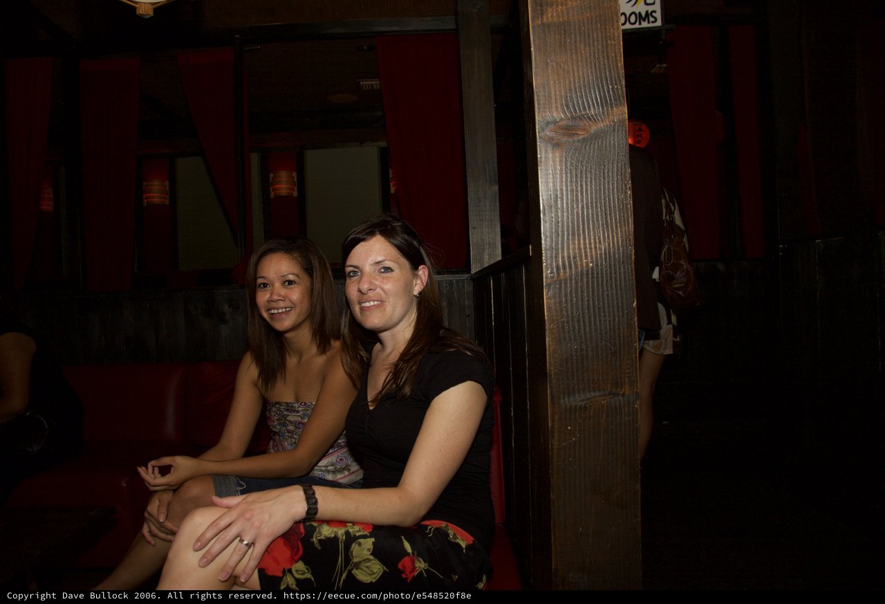 Two Women Smiling at a Dimly Lit Bar
