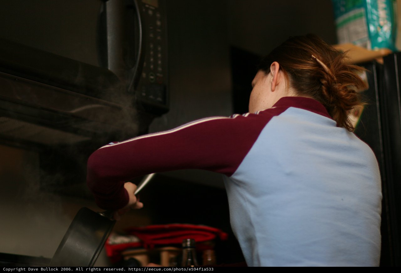 Woman Cooking at Stovetop in Dim Kitchen