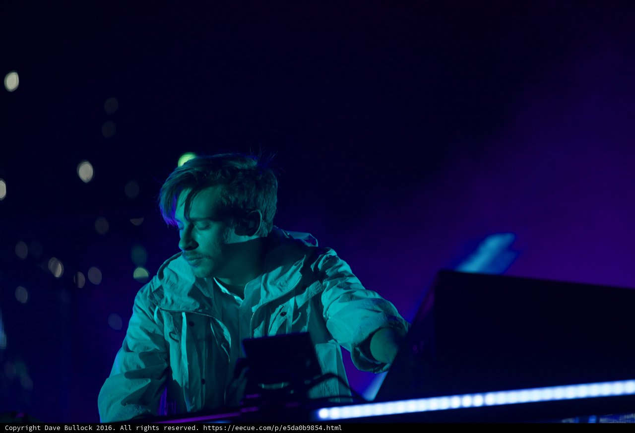 Flume in Concert Caption: Australian deejay Flume entertains the crowd at Coachella 2016, playing his keyboard and laptop while wearing a white jacket in the midst of an electric lighting and visual display on stage.