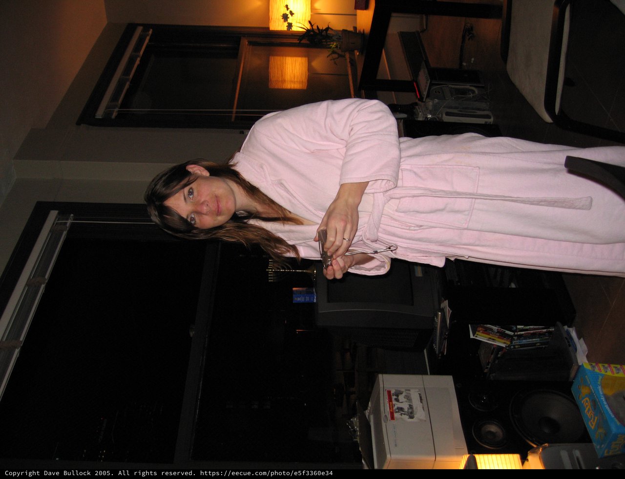 Woman in Pink Robe Standing in Dimly Lit Apartment