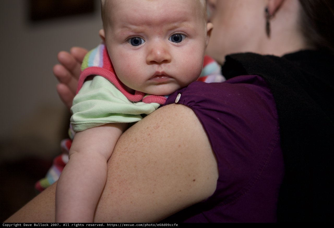 Wide-Eyed Baby Resting on Mother's Shoulder