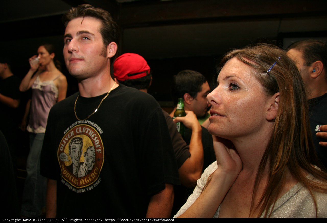 Couple Watching Intently at a Nighttime Bar Event