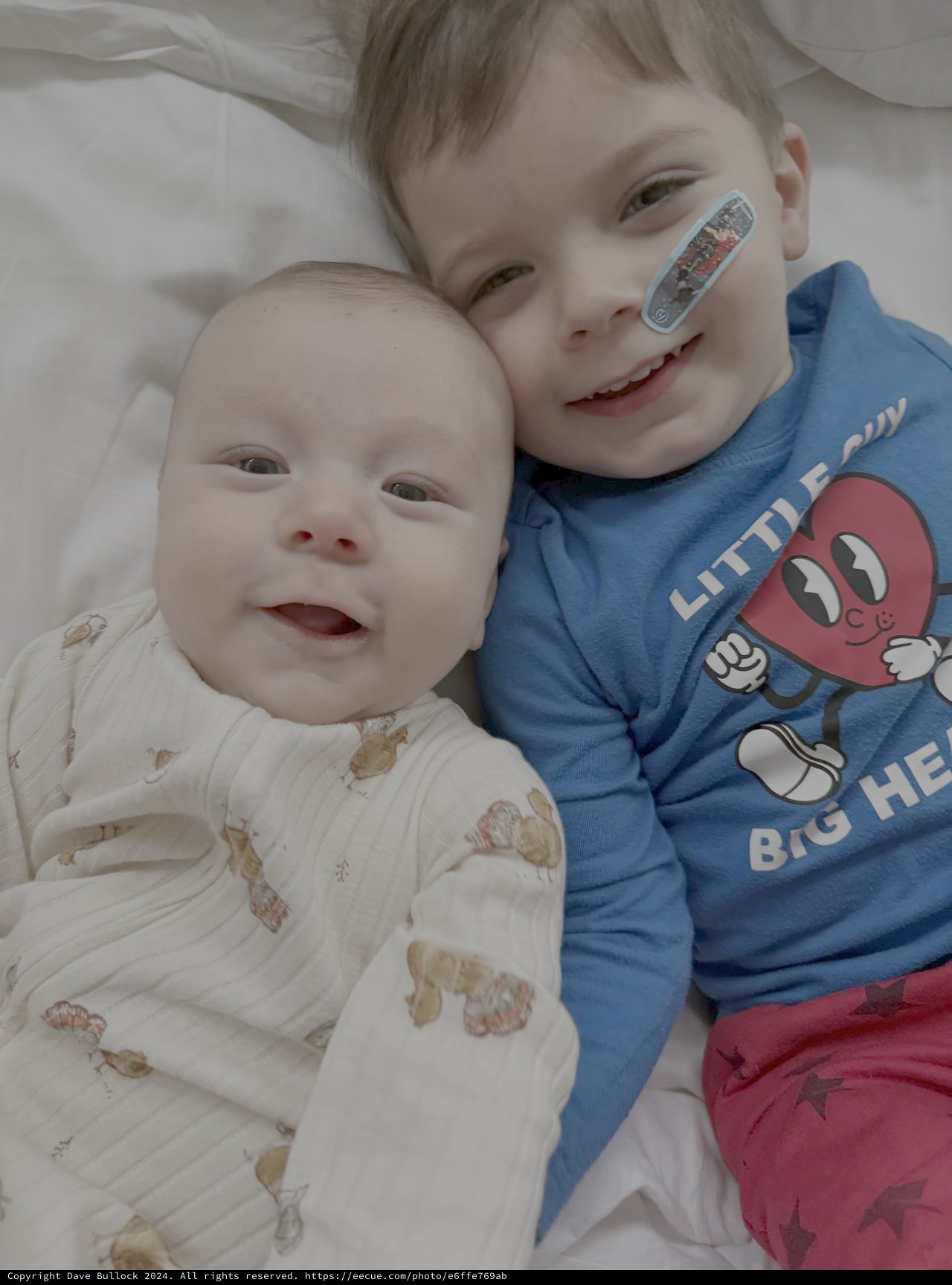 Two Young Children Cuddling in Hospital Bed