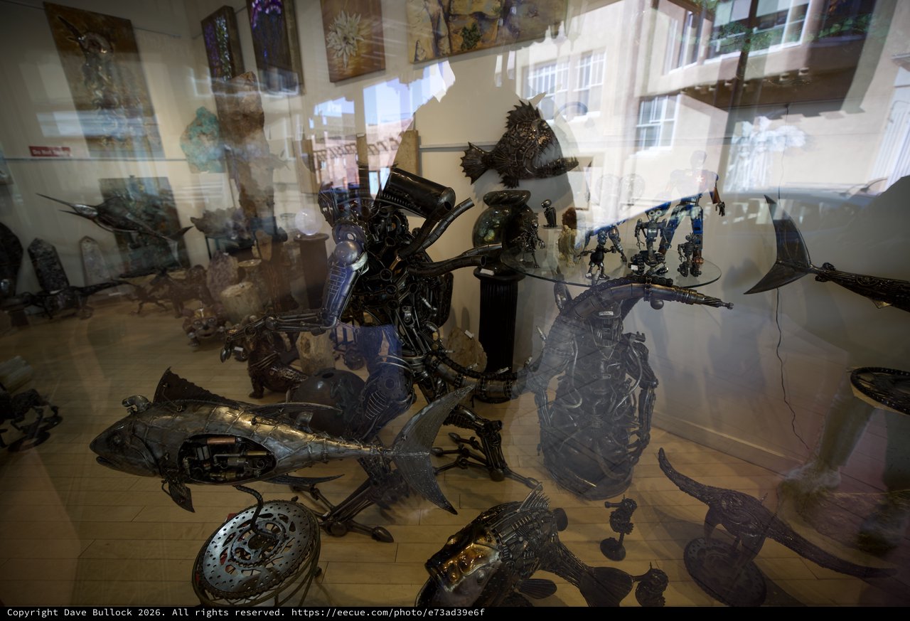 Metal Sculptures Displayed Behind Gallery Window Reflections