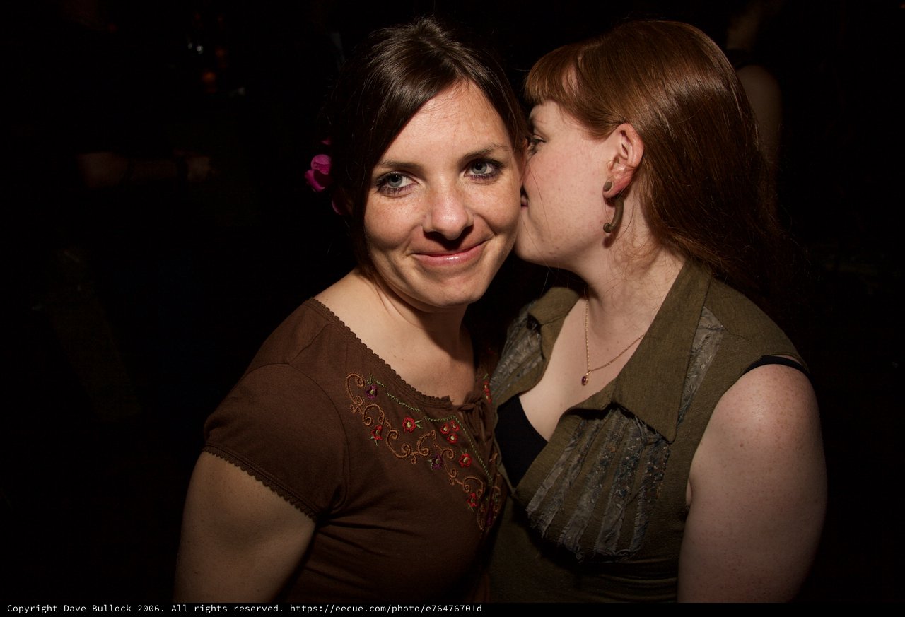 Two Friends Share a Playful Kiss at Art Walk