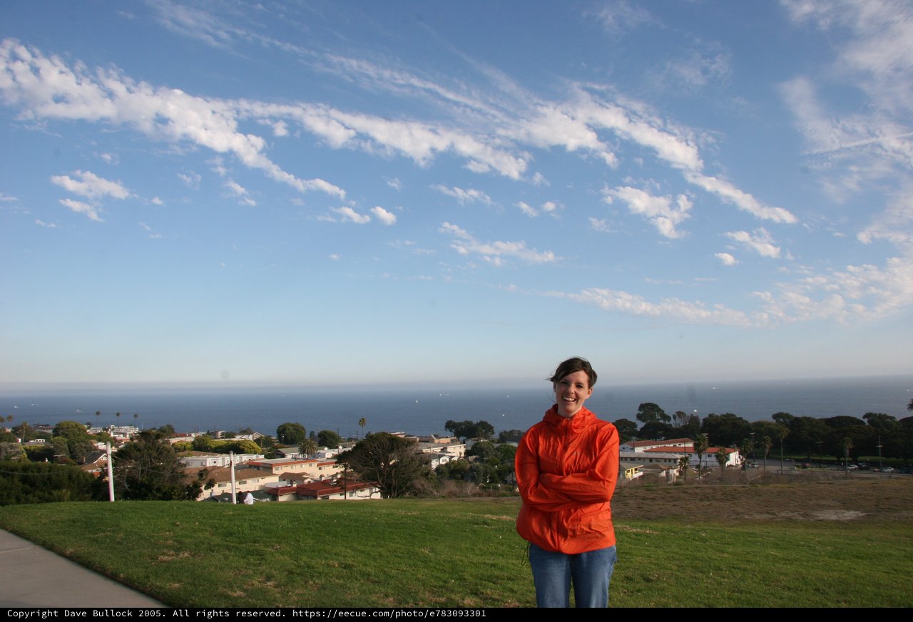 Woman in Orange Jacket Overlooking Coastal Town