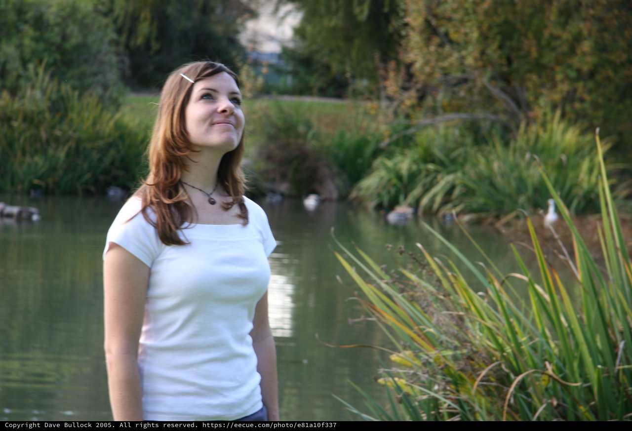 Young Woman Gazing Upward by a Tranquil Pond