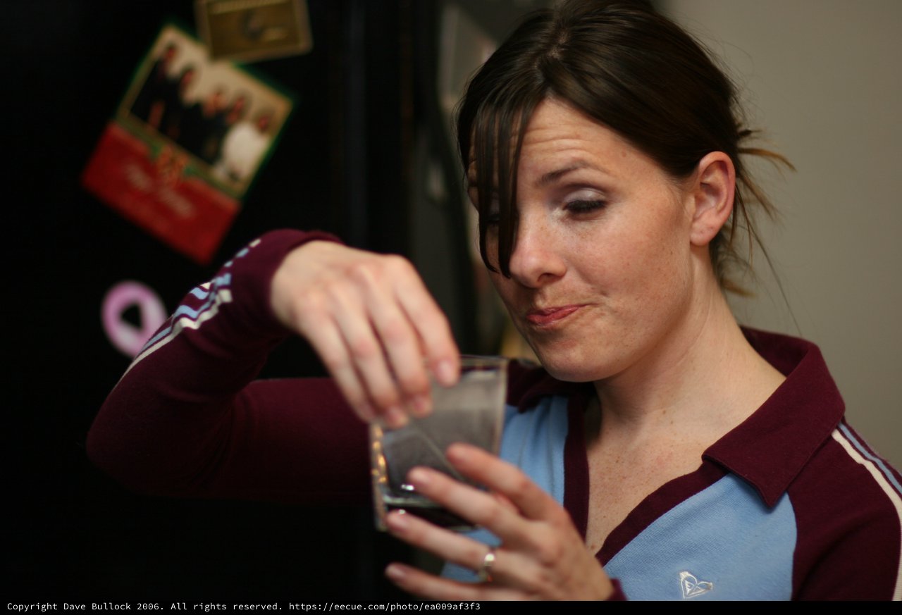 Woman Carefully Adding Something to a Glass