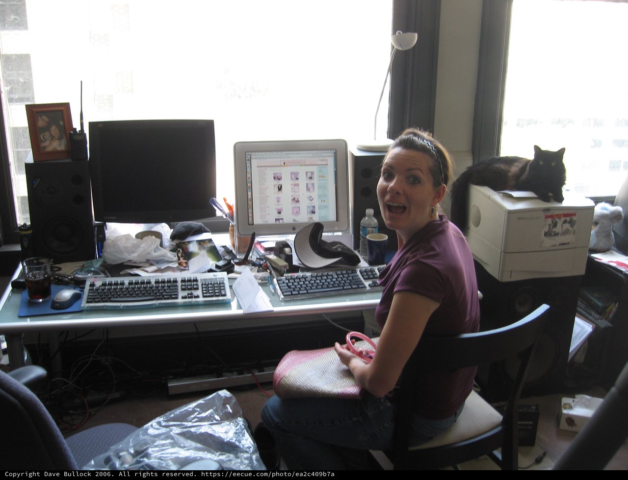 Surprised Woman at Cluttered Dual-Monitor Home Office