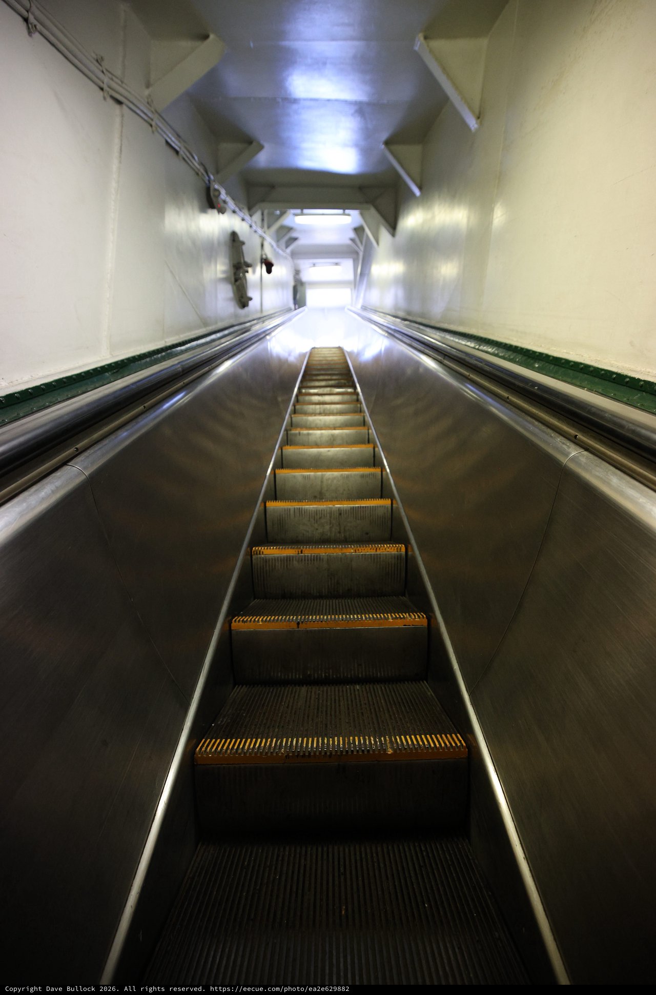 Ascending the Steep Escalator into Illuminated Transit Tunnel