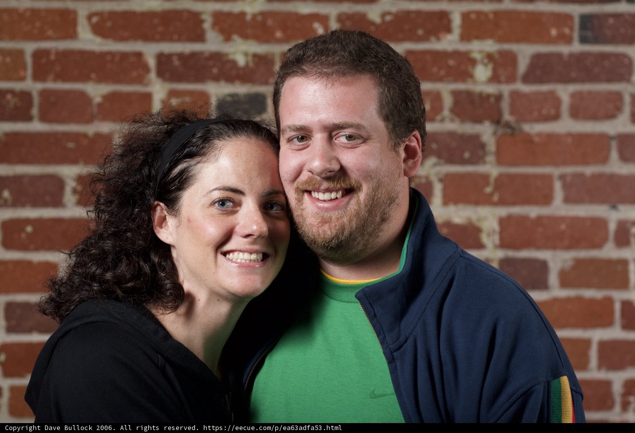 Happy Couple Poses in Front of Brick Wall