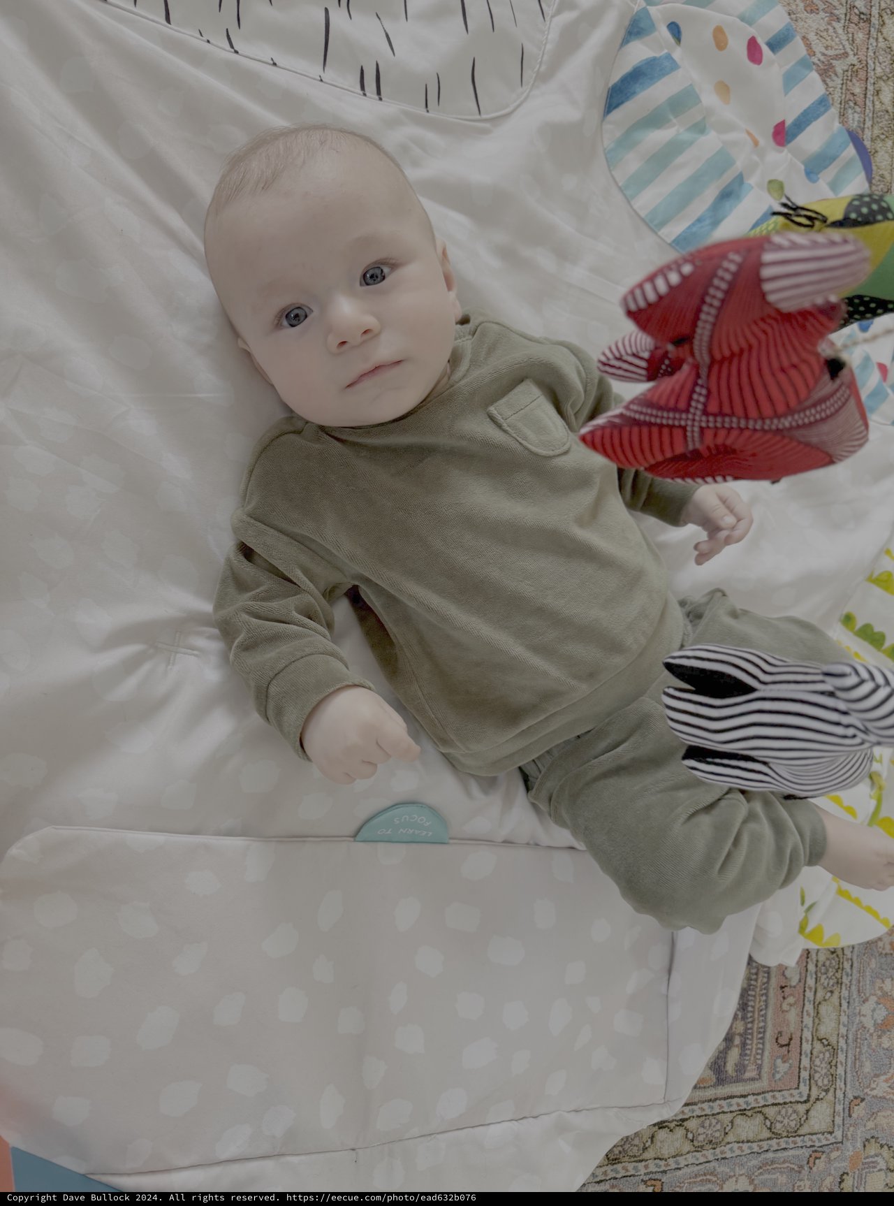 Baby in Green Outfit Lying on Bed