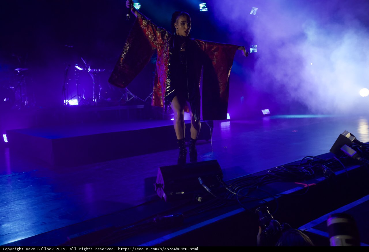 FKA twigs Stunning Full Body Arms Spread Wide Displaying Full Kimono Wings Red Brocade Gold Patterns Black Bodysuit Boots Face Visible Blue Purple Lighting