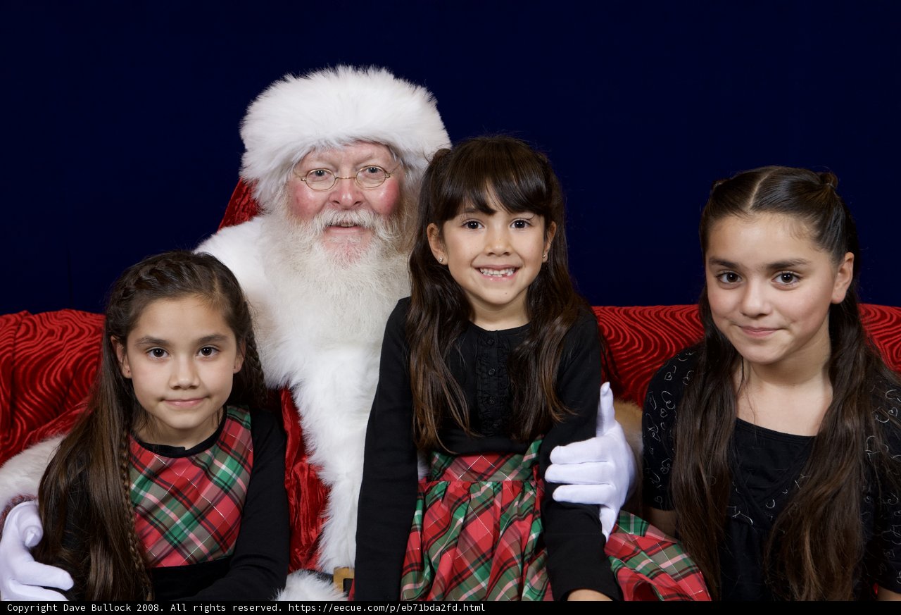 Santa Claus takes a picture with three adorable girls
