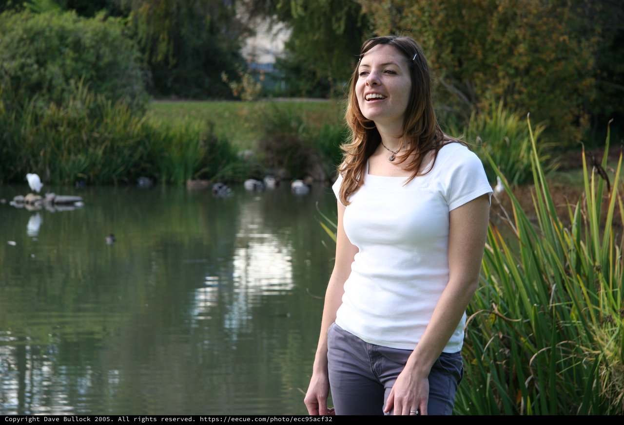 Joyful Woman Laughing by a Tranquil Park Pond