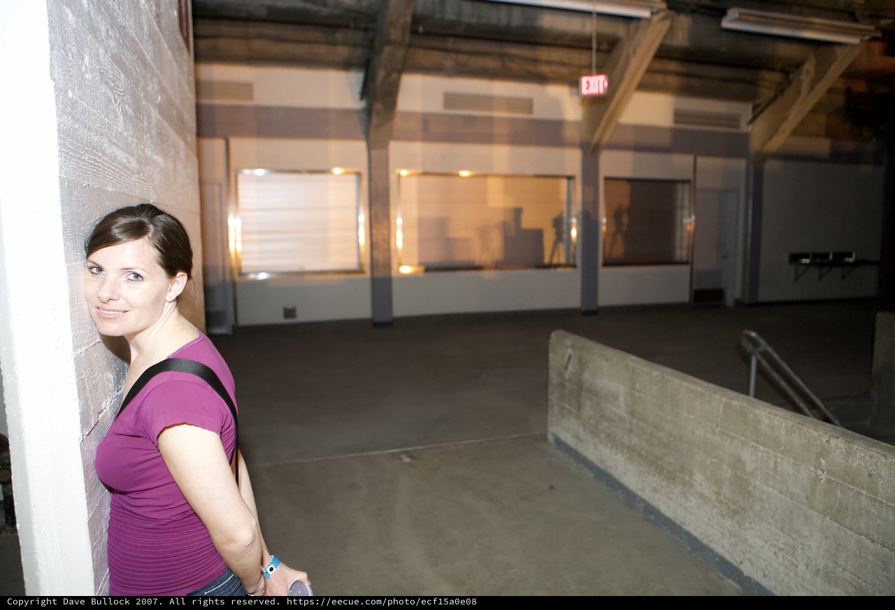 Woman Leaning Against Wall in Empty Warehouse Space